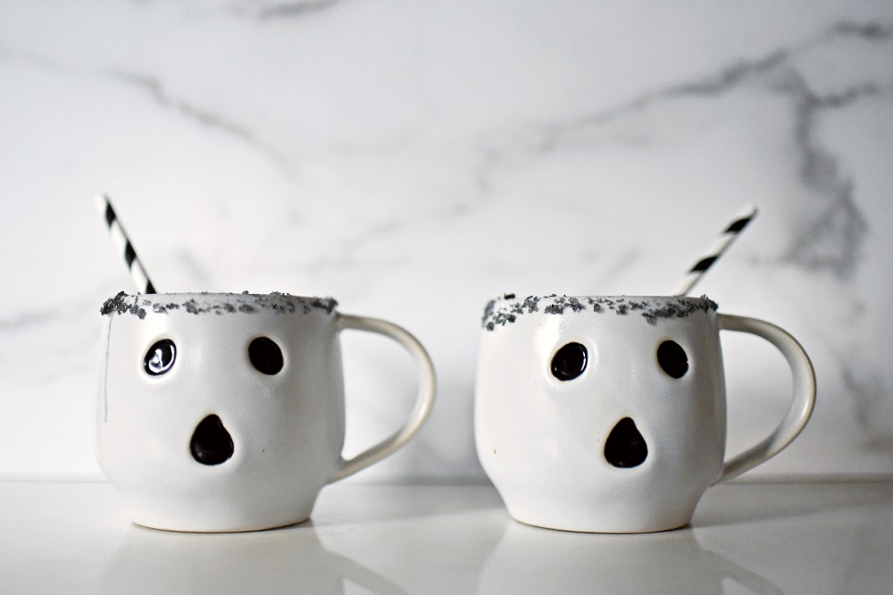 Halloween Orange Mango Jalapeno Margaritas with black lava salt featuring Gem & Bolt Mezcal served in ghost mugs from Pottery Barn. #gemandbolt #gemandboltmezcal #mezcalcocktail #mezcalmargarita #halloweenmargarita #halloweencocktail #ghostmug