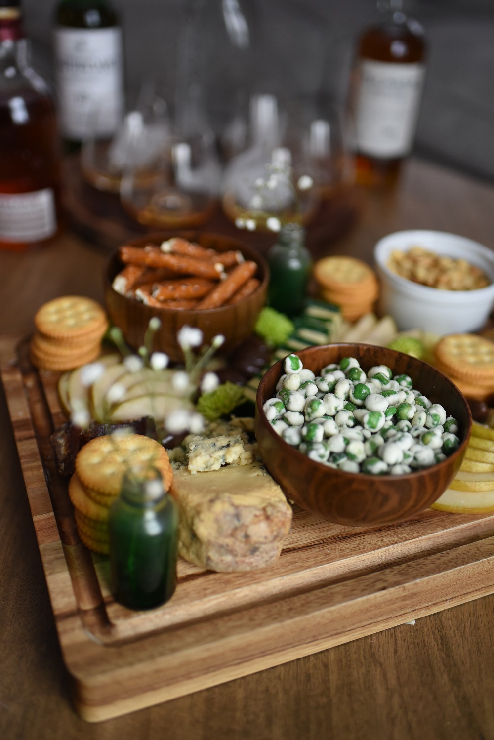 A St. Patrick's Day Cheese Board featuring Irish cheeses, salted pretzels, crackers, sliced pear, peanuts, wasabi peas, dates, and chocolates. #stpatricksdaycheeseboard #stpatricksdaysnacks #stpatricksdayrecipe