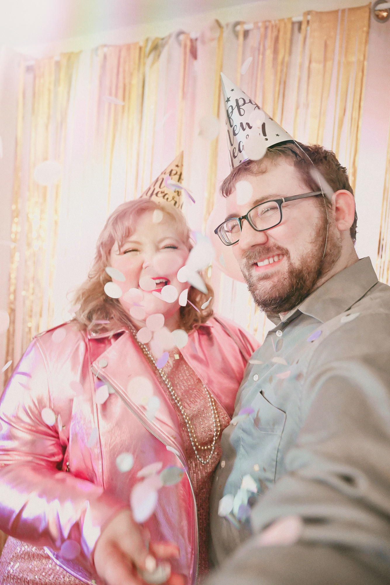 A Pink NYE Photoshoot | Celebrate New Year's Eve at home with a DIY backdrop using tinsel curtains, confetti, balloons, and party beads.
